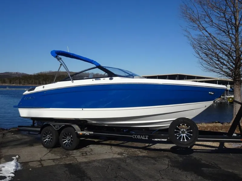 Slide: The Image of 2025 Cobalt R4 boat with blue hull on trailer by a lake. - 3