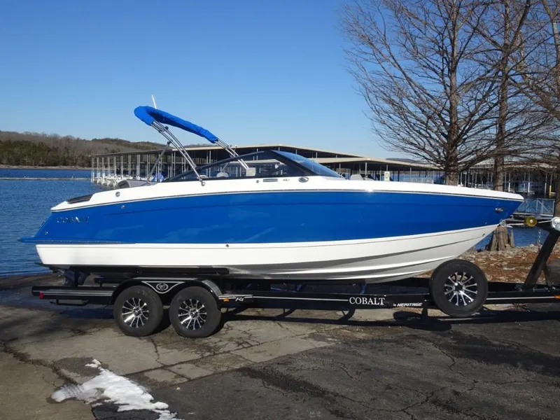 Slide: The Image of 2025 Cobalt R4 boat on trailer by lakeside, blue and white design. - 4