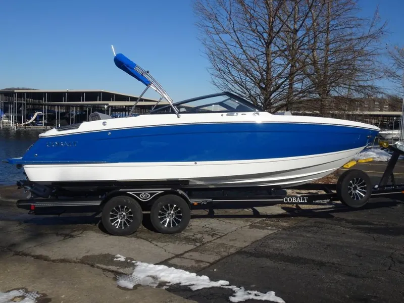 Slide: The Image of 2025 Cobalt R4 boat in blue and white on a trailer by the water. - 5