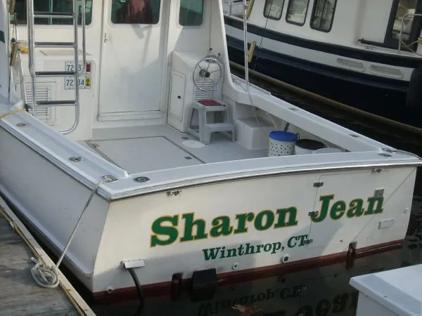 Slide: The Image of The boat "Sharon Jean" is docked, featuring an open stern area and a small chair. - 42