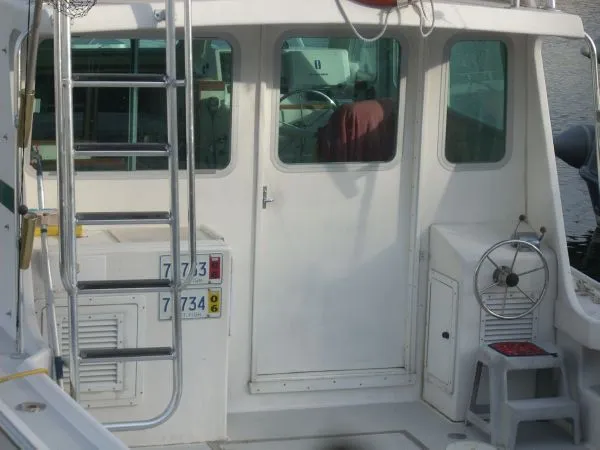 Slide: The Image of The image shows the stern of a 2000 Duffy Flybridge Sportfisherman with helm and ladder. - 48