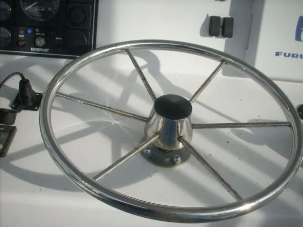 Slide: The Image of A shiny metal steering wheel on a boat, surrounded by instruments and control devices. - 22