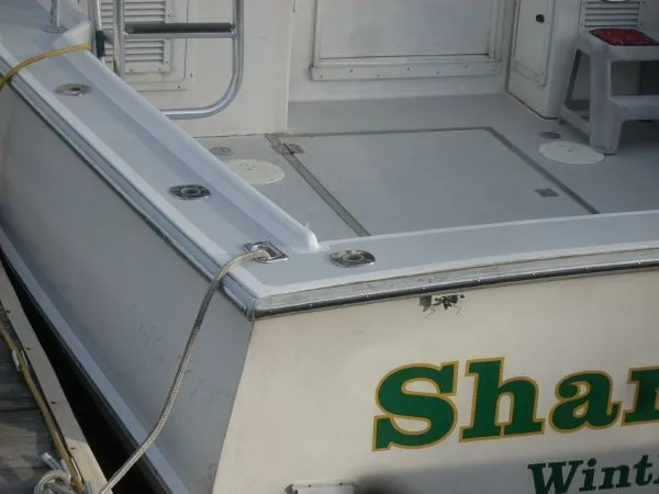 Slide: The Image of The image shows the stern of a 2000 Duffy Flybridge Sportfisherman, docked at a pier. - 38