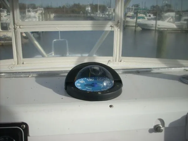 Slide: The Image of A compass is mounted on a boat's dashboard, overlooking a marina. - 23