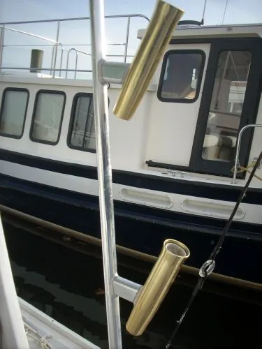Slide: The Image of A boat with brass fishing rod holders, with another boat docked in the background. - 17