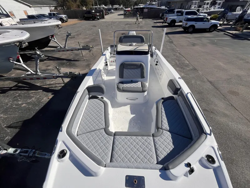 Slide: The Image of 2025 NauticStar 211 Hybrid boat with gray seating, parked outdoors. - 11