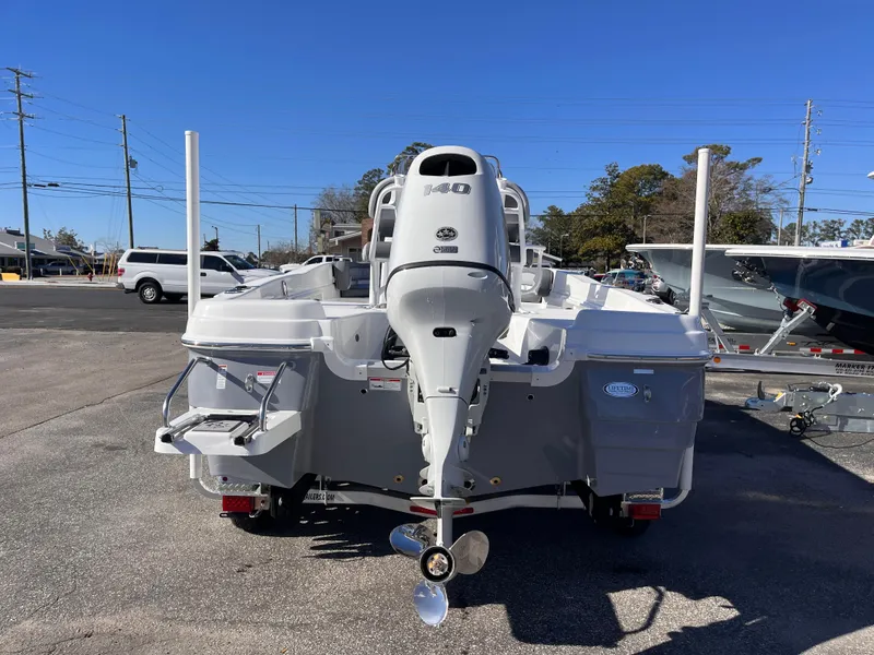 Slide: The Image of 2025 NauticStar 211 Hybrid boat, rear view, parked outdoors on a sunny day. - 3