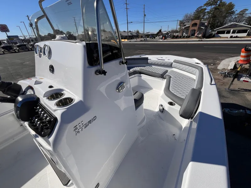 Slide: The Image of 2025 NauticStar 211 Hybrid boat interior with seating and console, parked outdoors. - 9