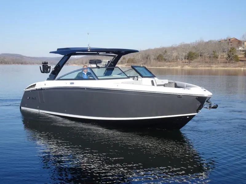 The Image of 2025 Cobalt R33 Surf boat cruising on a calm lake under clear skies. - 1