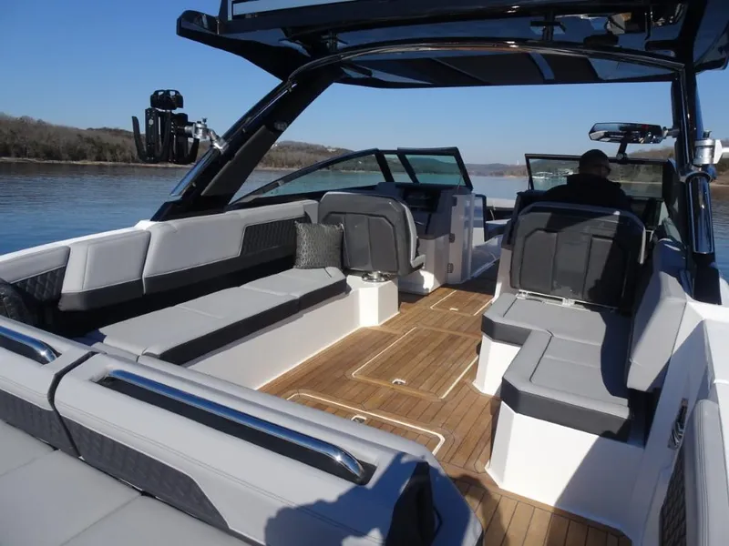 Slide: The Image of 2025 Cobalt R33 Surf boat interior with sleek seating and wooden flooring on a calm lake. - 11