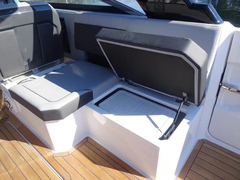 Slide: The Image of 2025 Cobalt R33 Surf boat interior with open storage compartment and cushioned seating. - 17