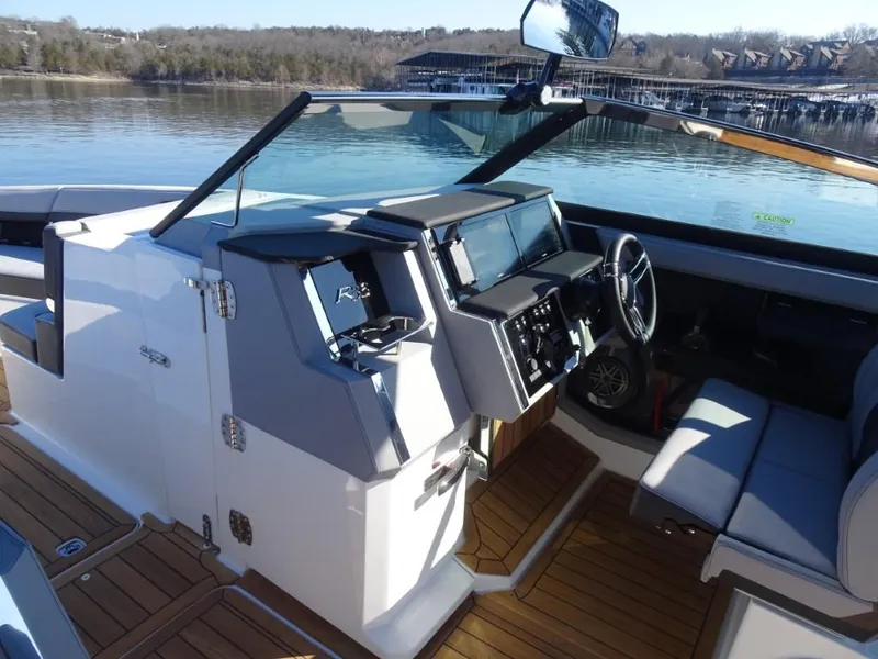 Slide: The Image of 2025 Cobalt R33 Surf boat interior with modern dashboard and seating, docked on a calm lake. - 27