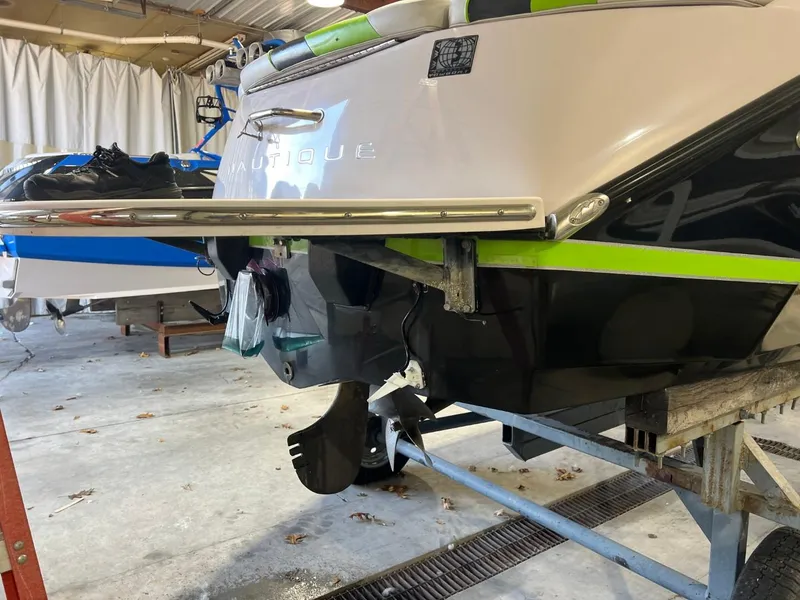 Slide: The Image of 2005 Nautique Super Air 210 boat in storage, showcasing rear view and propeller. - 19