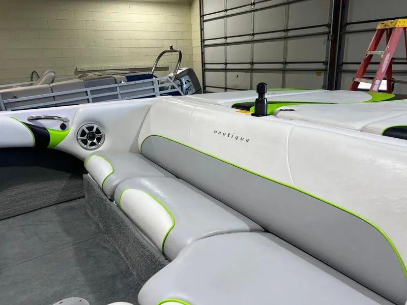 Slide: The Image of 2005 Nautique Super Air 210 interior with white and green seating in a garage. - 6