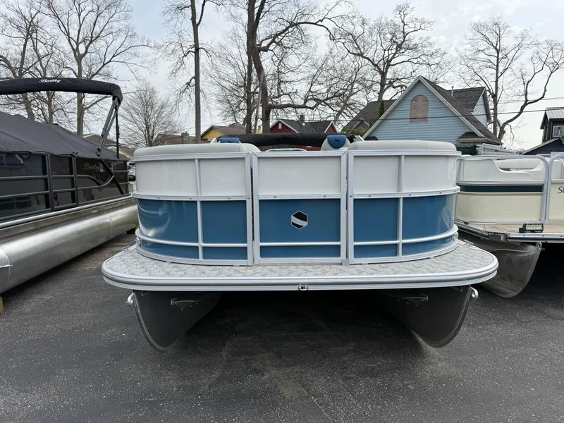 Slide: The Image of 2025 South Bay 224RS LE pontoon boat, blue and white, parked on pavement. - 2