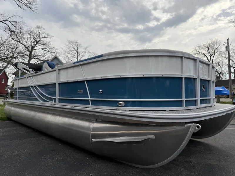 Slide: The Image of 2025 South Bay 224RS LE pontoon boat with blue and white exterior, parked outdoors. - 3