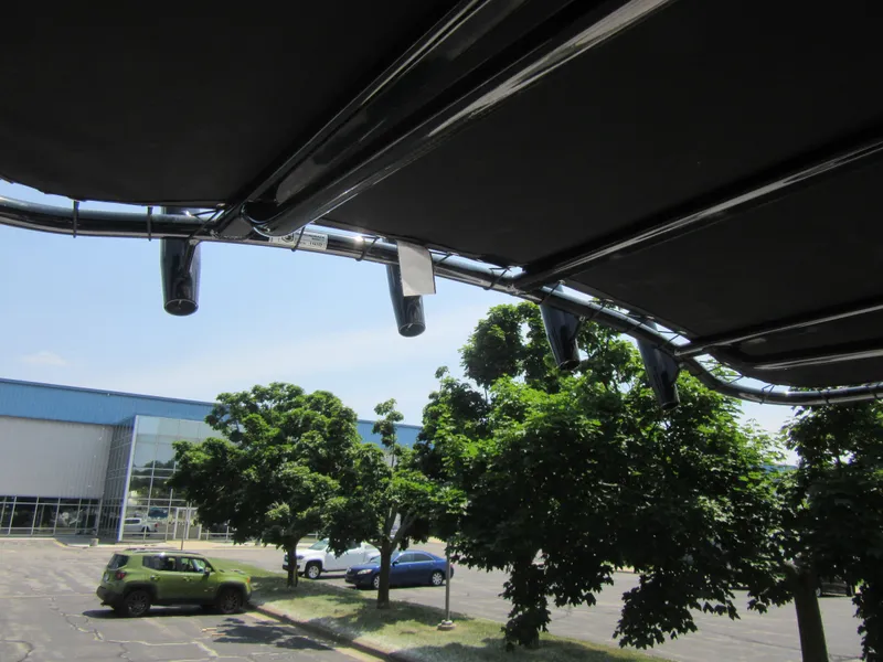 Slide: The Image of 2025 Robalo R202 Explorer boat canopy with trees and cars in the background. - 18