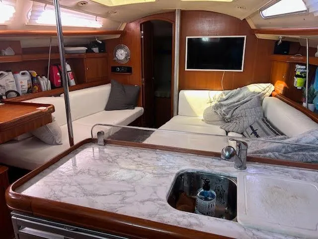 Slide: The Image of Interior of a 2006 Hunter 38 sailboat with white seating and wooden accents. - 18