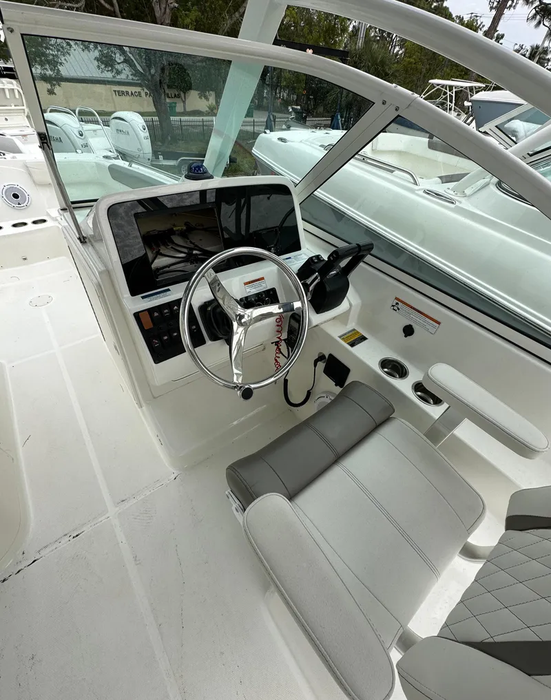 Slide: The Image of 2021 World Cat 230 DC boat cockpit with steering wheel and seating. - 5