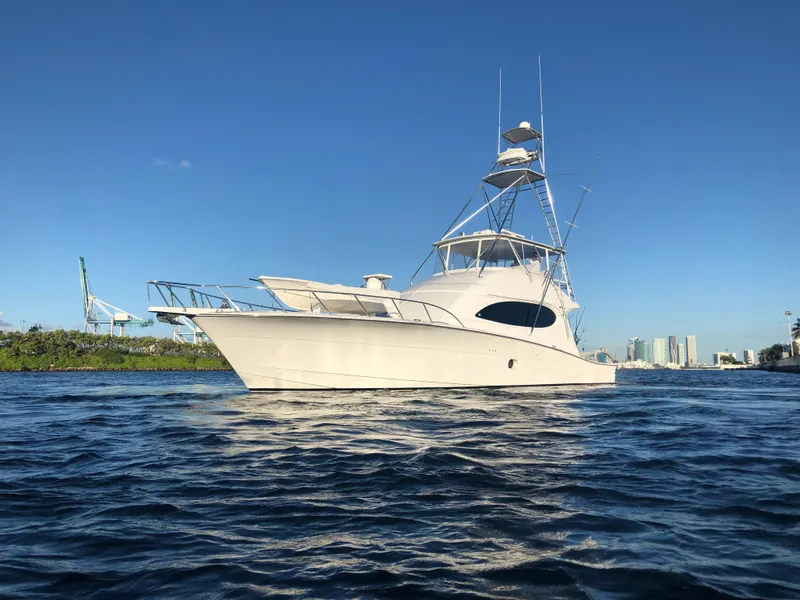 The Image of 2006 Hatteras 64 Convertible yacht on calm water under clear blue sky. - 0