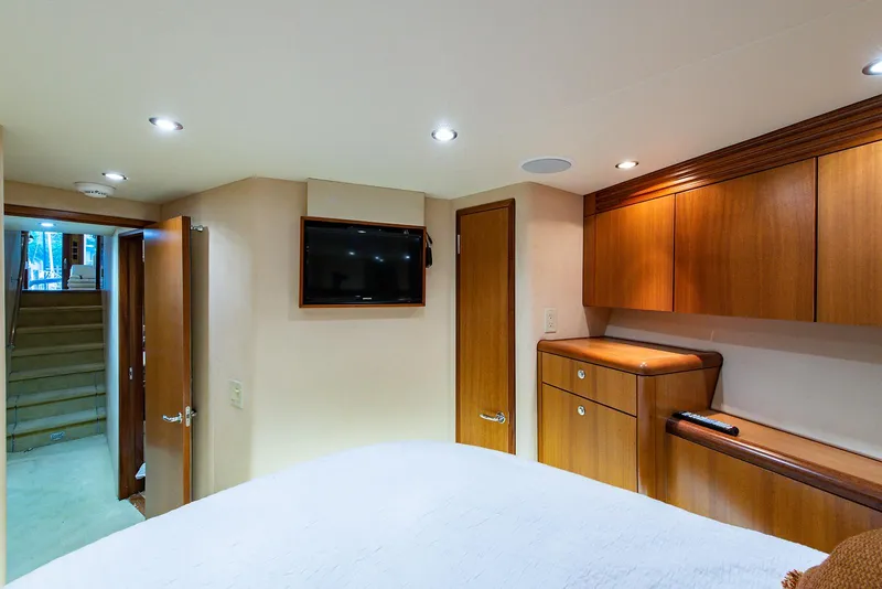 Slide: The Image of Interior of 2006 Hatteras 64 Convertible yacht bedroom with wood cabinetry and mounted TV. - 22