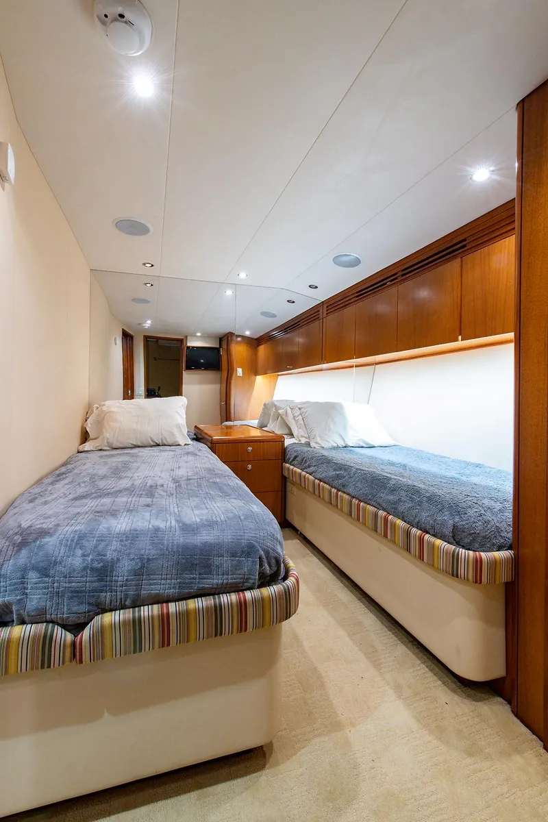 Slide: The Image of 2006 Hatteras 64 Convertible yacht cabin with twin beds and wooden cabinetry. - 31