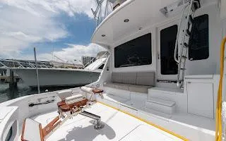 Slide: The Image of 2006 Hatteras 64 Convertible yacht docked, featuring spacious deck and seating area. - 6