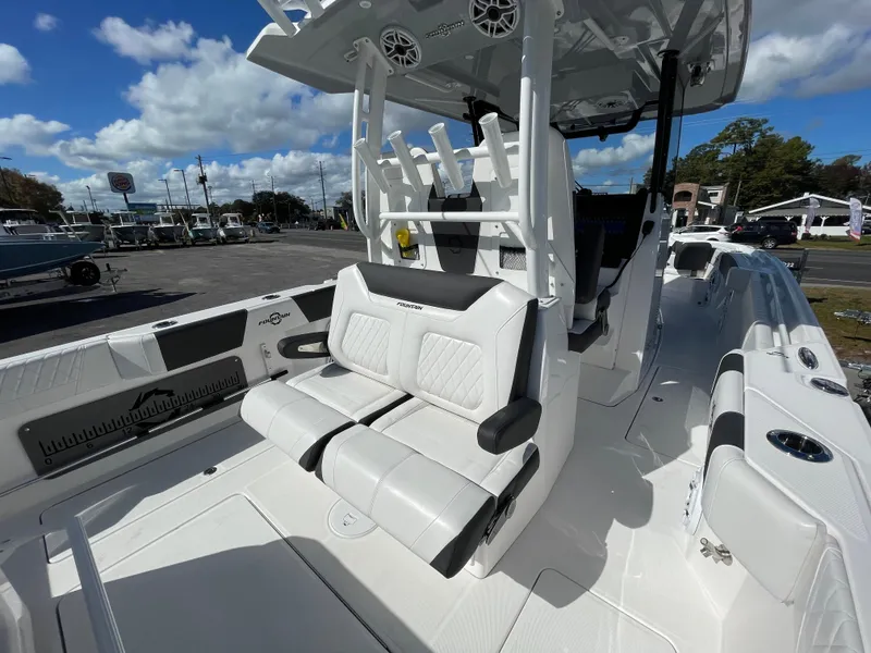Slide: The Image of 2023 Fountain 32 NX boat interior with white seating and rod holders under a blue sky. - 10