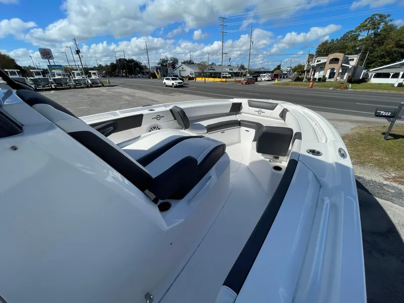 Slide: The Image of 2023 Fountain 32 NX boat with sleek seating, parked outdoors under a blue sky. - 16