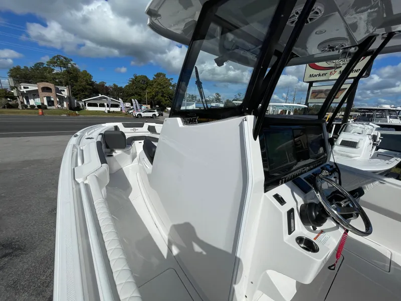 Slide: The Image of 2023 Fountain 32 NX boat cockpit with steering wheel and seating, under a partly cloudy sky. - 19