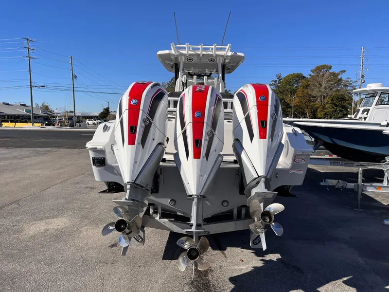 Slide: The Image of 2023 Fountain 32 NX boat with triple outboard engines, parked on a sunny day. - 4