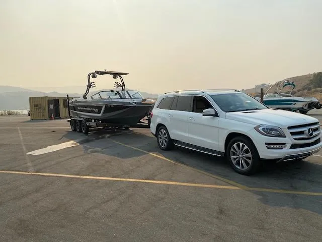 Slide: The Image of White SUV towing 2021 Nautique Super Air Nautique GS24 boat in parking lot. - 28