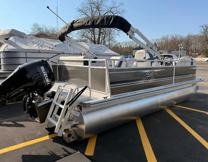 Slide: The Image of 2025 South Bay 20CR SE S pontoon boat with Suzuki outboard motor in a parking lot. - 17