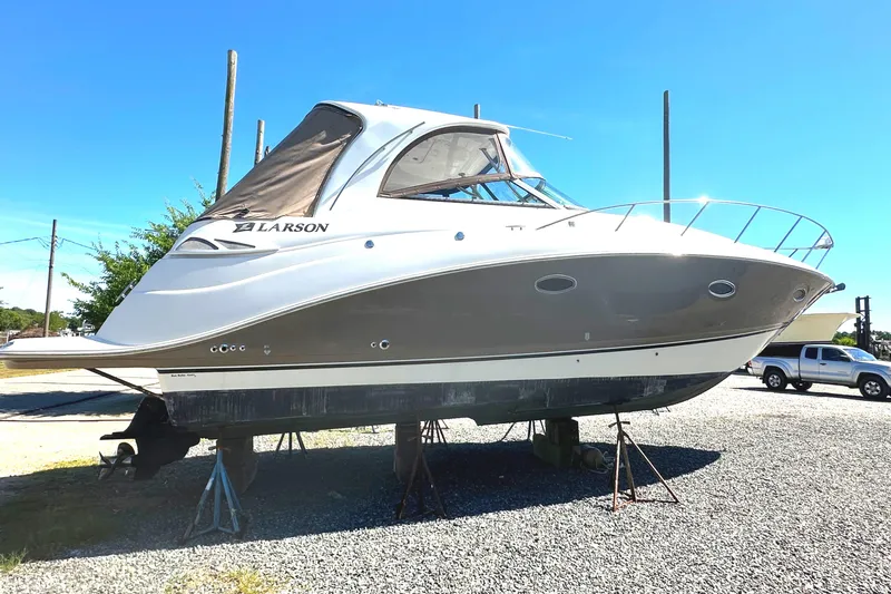 Slide: The Image of 2006 Larson Cabrio 350 boat on stands in a gravel lot under clear blue sky. - 11