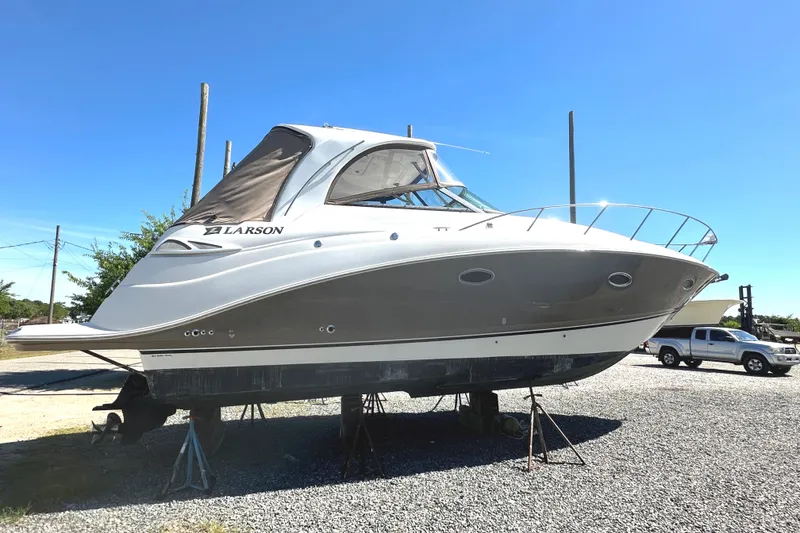 Slide: The Image of 2006 Larson Cabrio 350 boat on stands, parked on gravel under clear blue sky. - 12