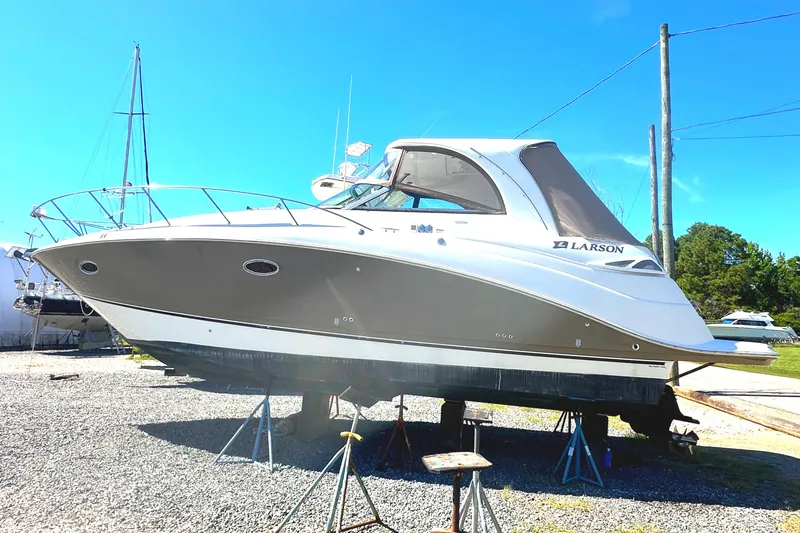 Slide: The Image of 2006 Larson Cabrio 350 boat on stands, displayed outdoors under clear blue sky. - 2