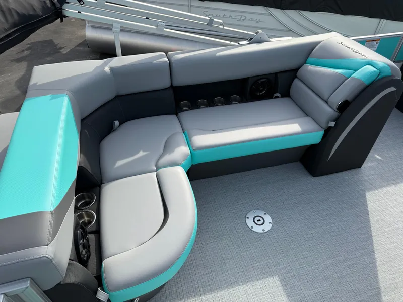 Slide: The Image of 2025 South Bay S222CR2 boat interior with teal and gray seating, cup holders, and modern design. - 15