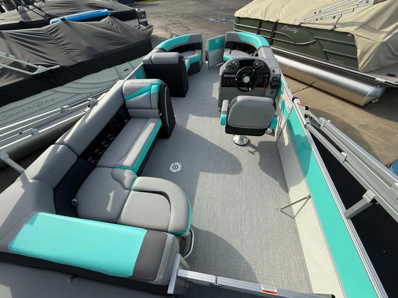 Slide: The Image of 2025 South Bay S222CR2 pontoon boat with teal and gray seating, spacious deck, and modern controls. - 21