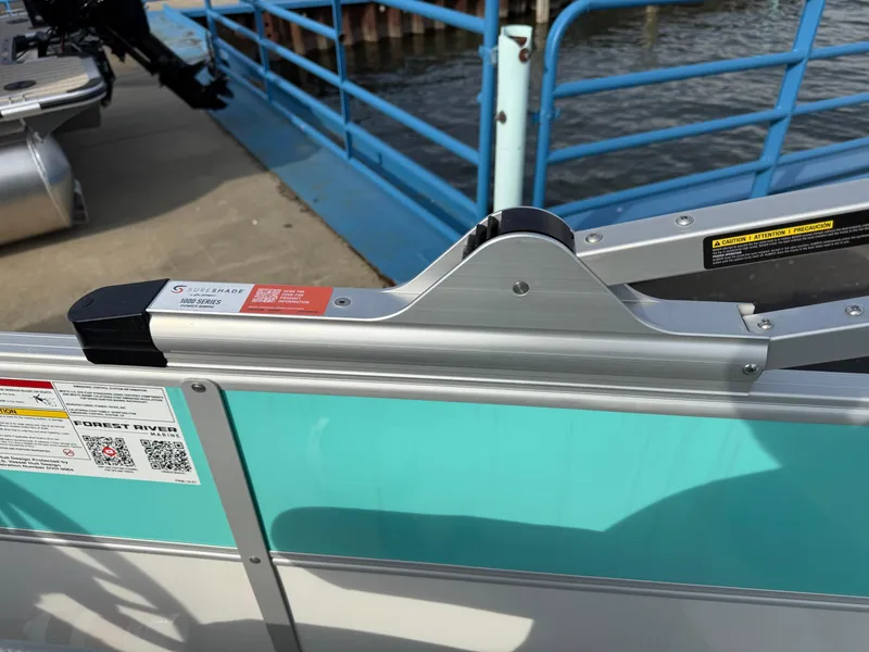 Slide: The Image of 2025 South Bay S222CR2 pontoon boat gate with safety latch, docked by blue railing. - 22