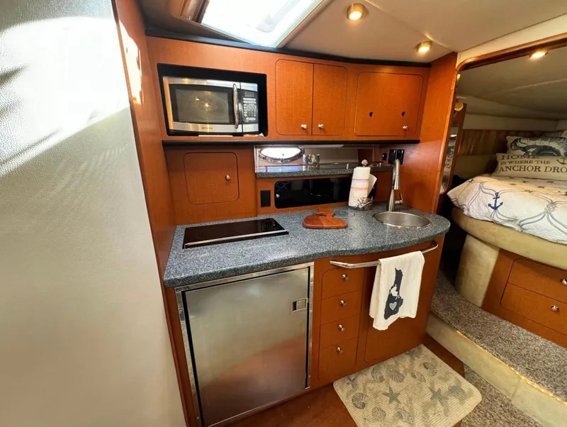 Slide: The Image of 2005 Chaparral Signature 350 yacht interior with kitchenette, featuring microwave, sink, and cozy sleeping area. - 7