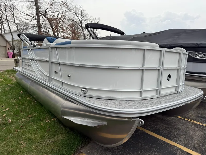 Slide: The Image of 2025 South Bay 220RS LE pontoon boat parked on grass near trees. - 1