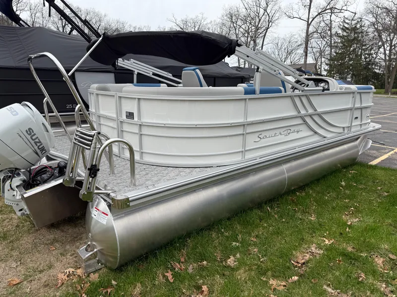 Slide: The Image of 2025 South Bay 220RS LE pontoon boat with Suzuki outboard motor, parked on grass. - 20