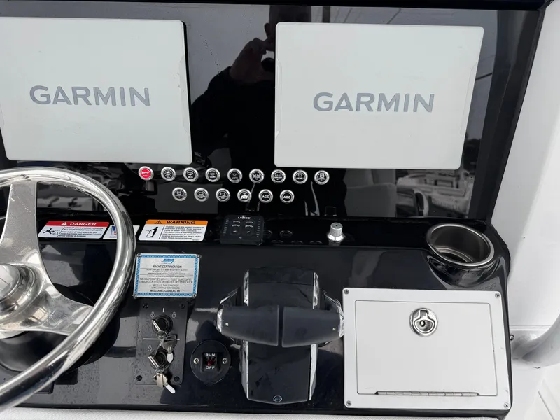 Slide: The Image of 2025 Wellcraft 263 Fisherman dashboard with dual Garmin displays and steering wheel. - 19