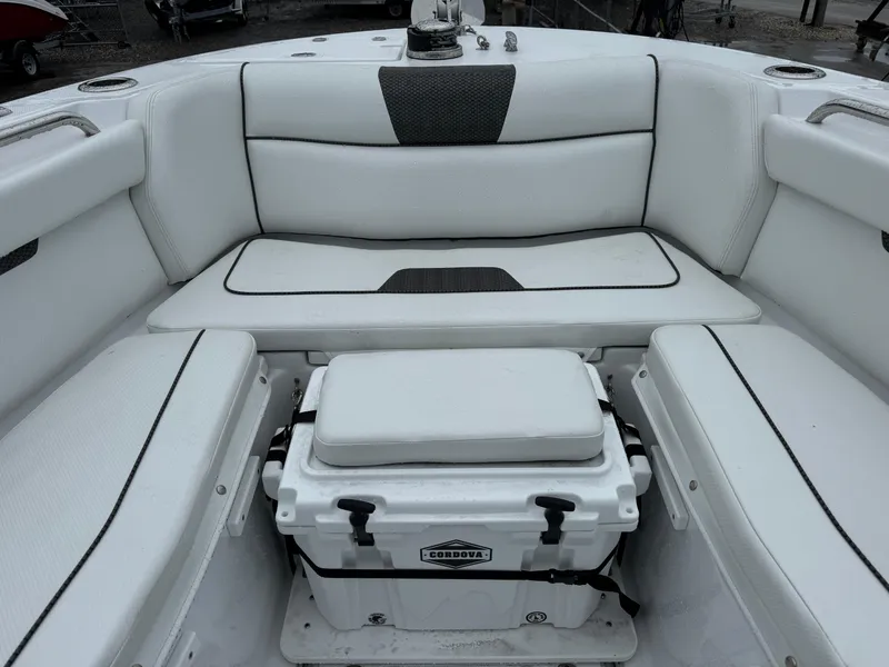 Slide: The Image of 2025 Wellcraft 263 Fisherman boat interior with white cushioned seating and cooler. - 31