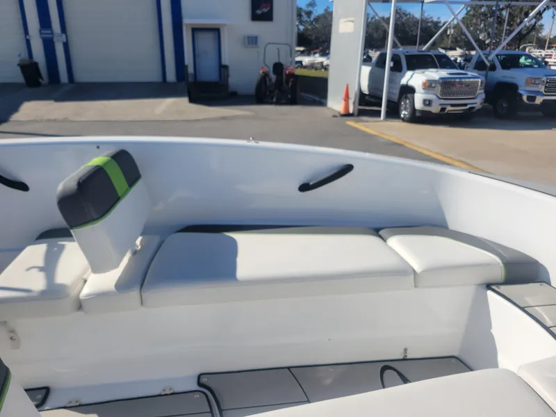 Slide: The Image of 2021 Tahoe T16 boat interior with white seating and green accents, parked near trucks. - 13