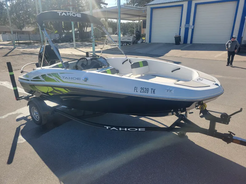 Slide: The Image of 2021 Tahoe T16 boat on trailer, parked outdoors, with canopy and vibrant design. - 2