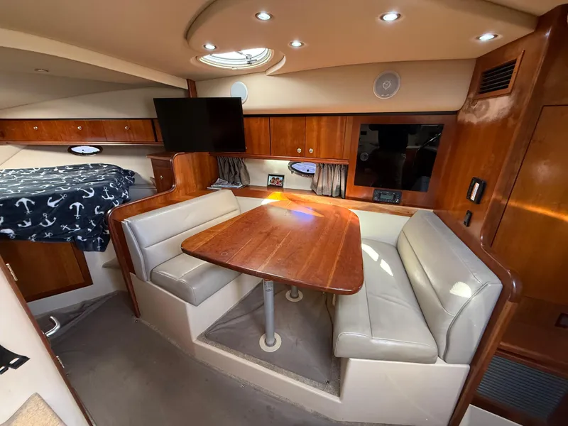 Slide: The Image of 2005 Cruisers Yachts 340 Express interior with dining area, TV, and cozy seating. - 20