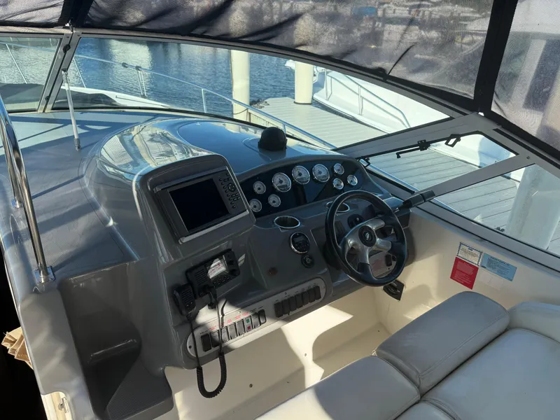 Slide: The Image of 2005 Cruisers Yachts 340 Express helm with steering wheel and navigation controls. - 10