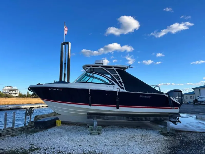Slide: The Image of 2014 Pursuit DC 265 Dual Console boat on a lift, clear sky background. - 4