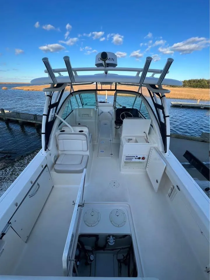 Slide: The Image of 2014 Pursuit DC 265 Dual Console boat on trailer, parked on grass under cloudy sky. - 8